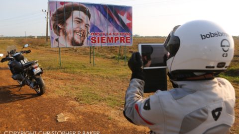 Motorcyclist photographs a Che Guevara billboard, Cuba; copyright Christopher P Baker
